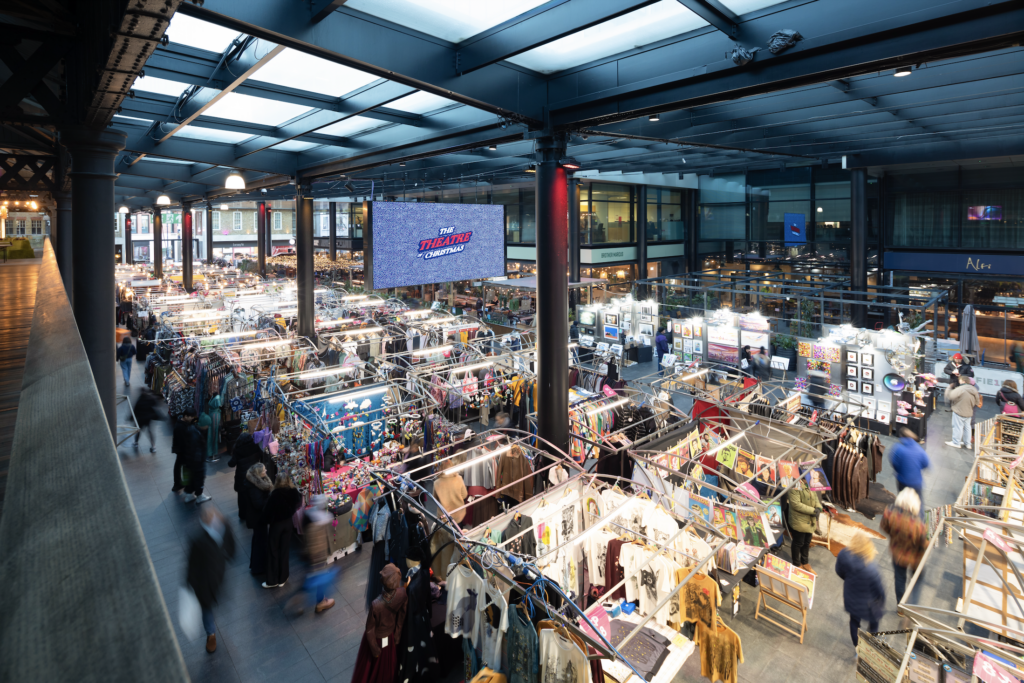An elevated view of visitors wandering around stalls at Spitalfields market at Christmas time