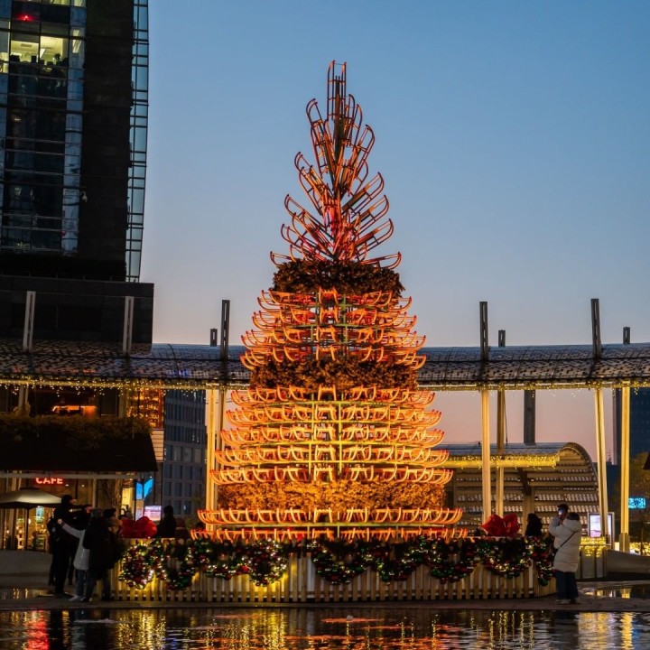 A Christmas tree installation lit up at nighttime as part of We Are Placemaking's festive activation in Portanuova, a modern business district in Milan, Italy